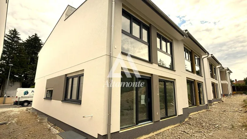 Moderne Neubaufassade mit großen Fenstern und noch unfertigem Außenbereich.