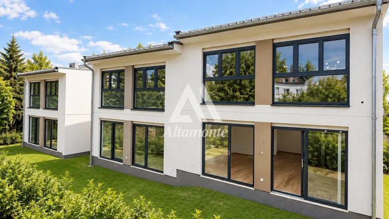 Moderne Doppelhaushälfte mit großen Fenstern und weißer Fassade, umgeben von Grünflächen.