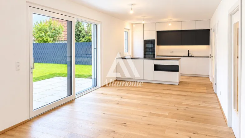 Heller offener Wohn-Essbereich mit moderner Küche, Holzboden und direktem Zugang zum Garten.