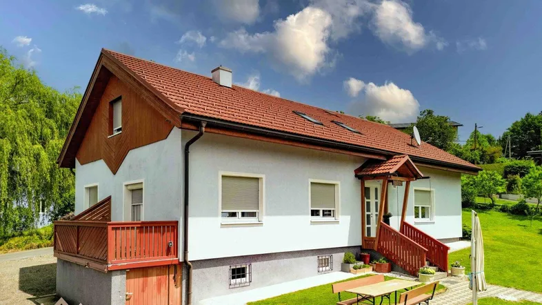Freistehendes Einfamilienhaus mit Satteldach, Garten und kleiner Terrasse im Grünen.