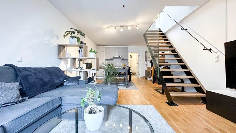 Geräumiger offener Wohn- und Essbereich mit moderner Treppe, Parkettboden und integrierter Küche.