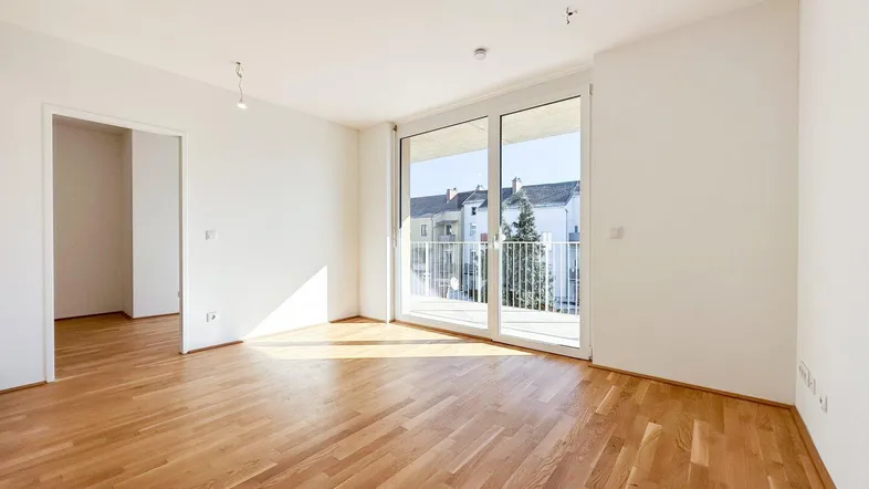 Helles Wohnzimmer mit Parkettboden und Zugang zu einem sonnigen Balkon, ideal für entspannte Stunden.