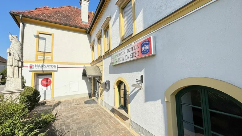 Fassade eines historischen Gebäudes mit gelben Akzenten und einem Restaurant-Schild unter blauem Himmel.