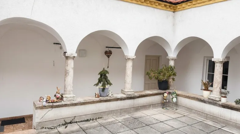 Historischer Innenhof mit Arkaden, Steinsäulen und gefliestem Boden, der zum Verweilen einlädt.