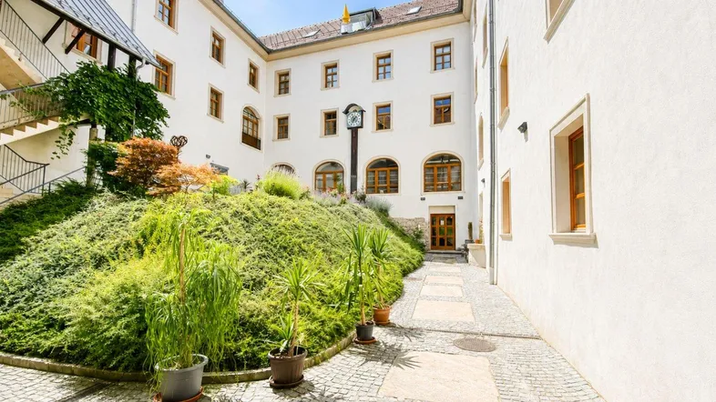 Malerischer Innenhof mit üppiger Bepflanzung und Kopfsteinpflaster.