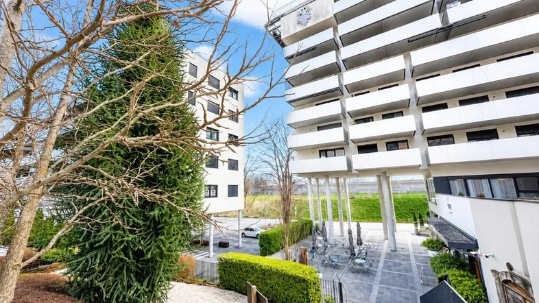 Blick auf moderne Wohngebäude mit Balkonen und einem begrünten Innenhof mit Sitzgelegenheiten.