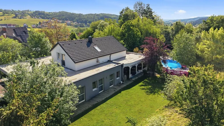 Luftaufnahme des Hauses mit großem Garten, Pool und umgebender grüner Landschaft.