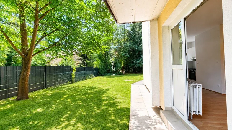 Gepflegter Gartenbereich mit Rasenfläche und direktem Zugang zu einer gefliesten Terrasse.