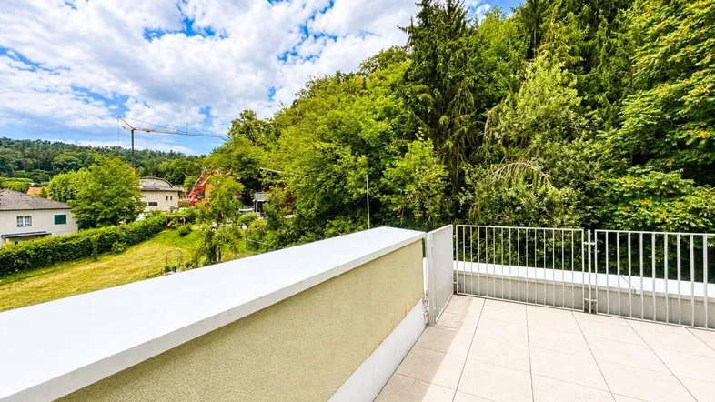 Geräumige Terrasse mit Fliesenboden und Blick auf die umliegende grüne Landschaft.