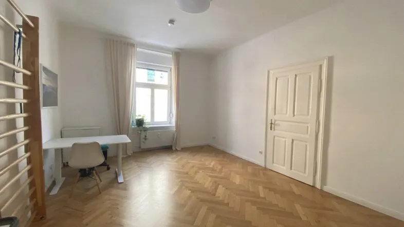 Heller Raum mit Fischgrätparkett, weißen Wänden und einem Fenster, ideal als Büro oder Schlafzimmer.
