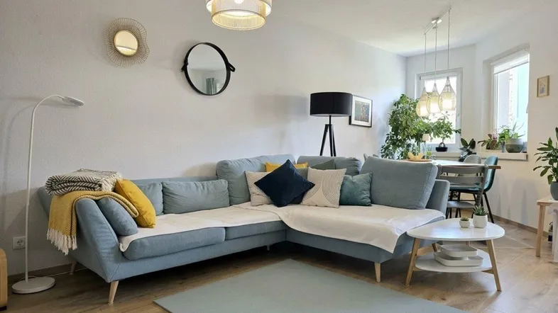 Helles Wohn- und Esszimmer mit bequemer Eckcouch, Esstisch und Zugang zum Balkon.