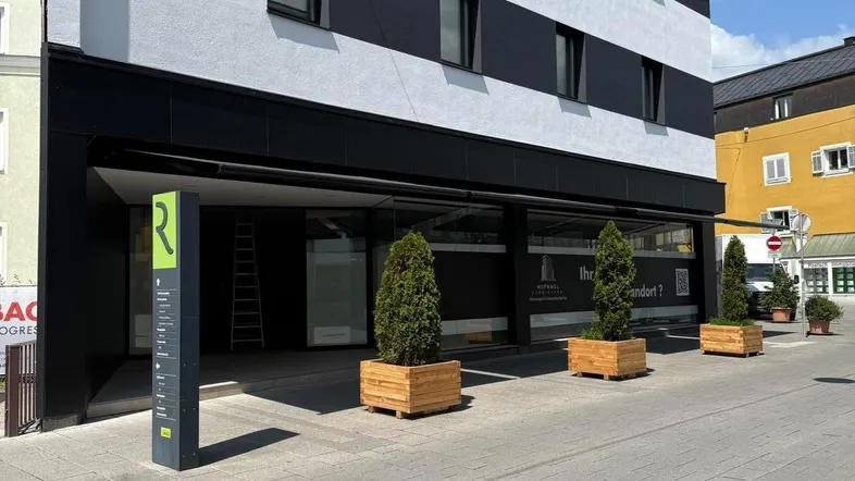 Moderne Geschäftsfassade mit schwarz-weißen Streifen und großen Schaufenstern im Erdgeschoss.