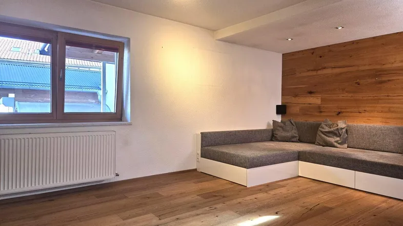 Helles Wohnzimmer mit Holzboden, einer modernen Sitzbank und einer Holzakzentwand.