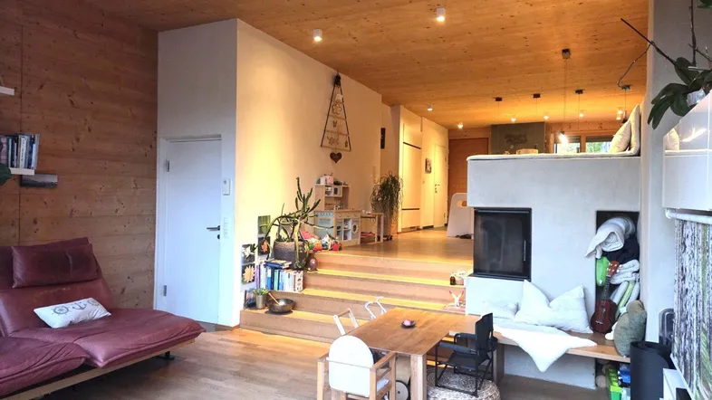 Geräumiges Wohnzimmer mit Holzvertäfelung, Parkettboden und integriertem Kaminbereich, der zum Entspannen einlädt.