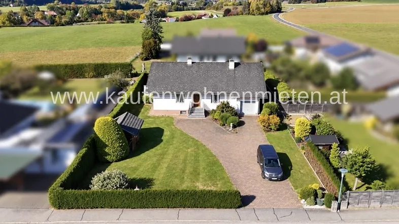 Luftaufnahme eines Einfamilienhauses mit gepflegtem Garten und Zufahrt in ländlicher Umgebung.