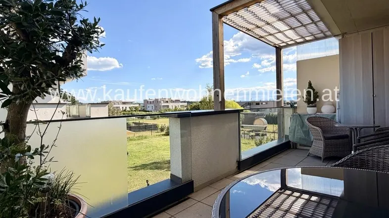 Geräumige Terrasse mit Pergola, modernen Glasgeländern und weitem Blick ins Grüne.