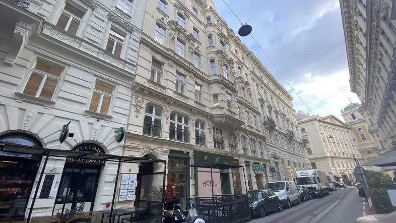 Historisches Gebäude mit klassischer Fassade und Geschäften im Erdgeschoss an einer belebten Straße.