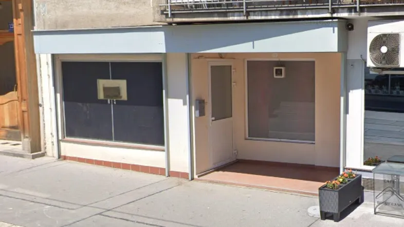 Vorderansicht eines Geschäftsgebäudes mit großen Schaufenstern und einem Eingangsbereich an einer Straße.