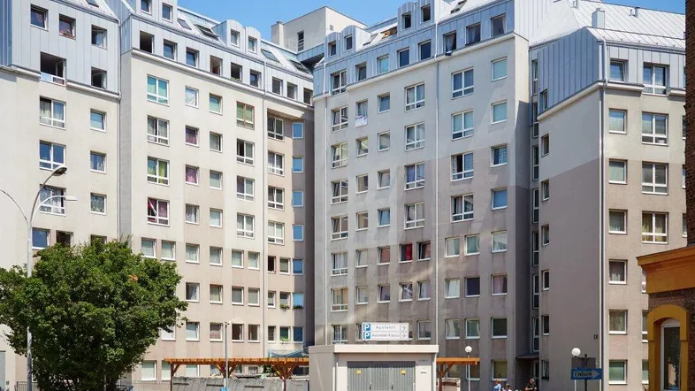 Mehrere Wohngebäude mit moderner Architektur und Mansarddächern in einer städtischen Umgebung.