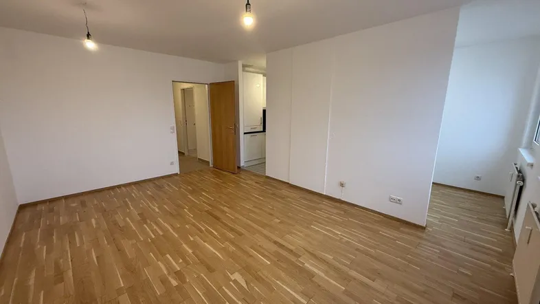 Helles, leeres Zimmer mit Parkettboden und weißen Wänden, bereit zur individuellen Gestaltung.