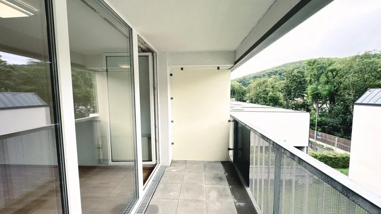 Geräumiger Balkon mit Fliesenboden und Blick auf die grüne Umgebung und die Hügel.