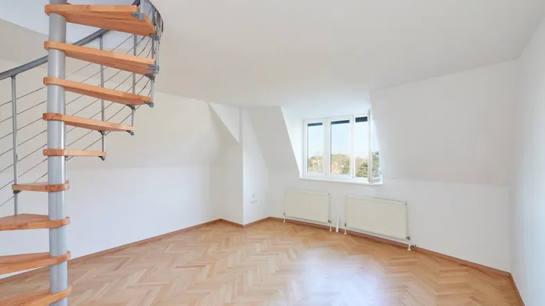 Helles Zimmer im Dachgeschoss mit eleganter Wendeltreppe und Fischgrätparkettboden.