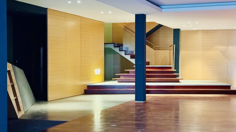 Großer, offener Innenraum mit Holzfußboden, einer Treppe und einer Säule in der Mitte.