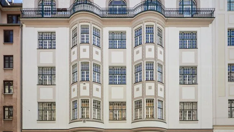 Elegante Stadtvilla mit klassischer Architektur, Erkerfenstern und schmiedeeisernen Balkonen an einer städtischen Straße.