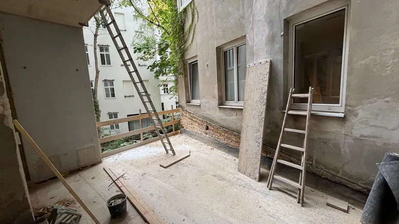 Baustelle einer zukünftigen Terrasse mit Blick auf den Innenhof und angrenzende Gebäude.