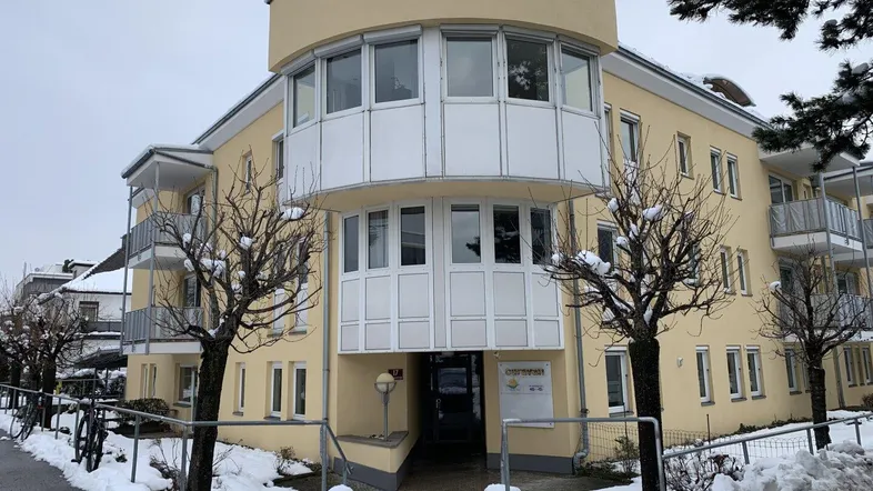Gelbes Mehrfamilienhaus mit runder Fassade und Balkonen, umgeben von Schnee im Winter.