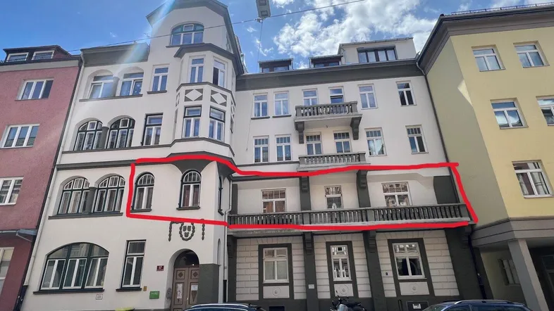 Historische Fassade eines Mehrfamilienhauses mit Balkonen und Straßenansicht in der Stadt.