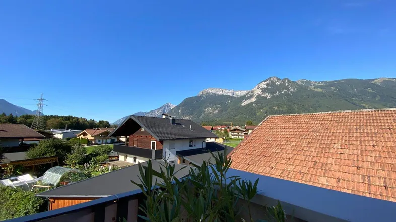 Panoramablick von der Terrasse auf die umliegende Berglandschaft und die Dächer der Nachbarschaft.