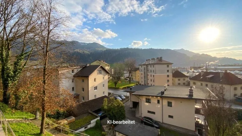 Panoramablick auf eine Wohngegend mit Bergen im Hintergrund unter einem sonnigen, blauen Himmel.