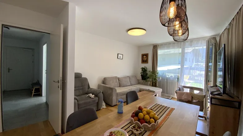 Heller Wohn- und Essbereich mit Holzboden, großem Esstisch und gemütlicher Sofaecke.