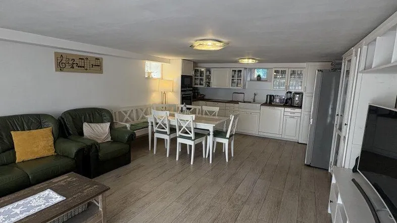 Helles, offenes Wohnzimmer mit integrierter Küche, Essbereich und modernem Bodenbelag.