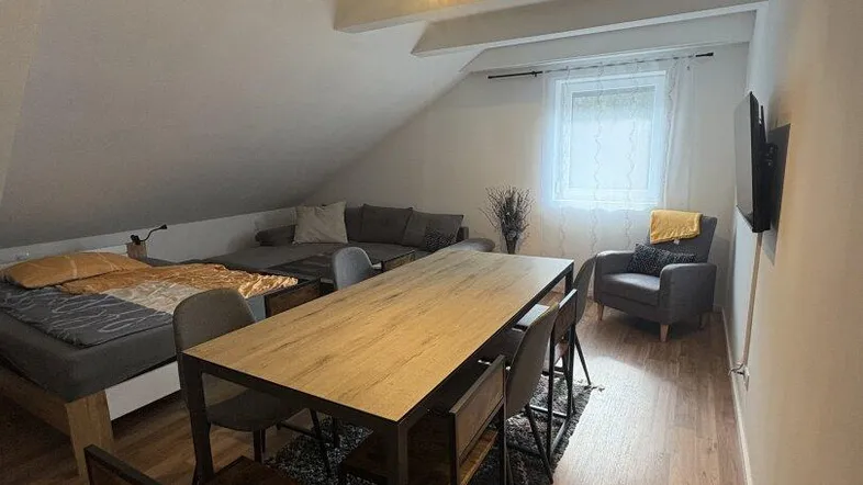 Gemütlicher Wohn- und Essbereich im Dachgeschoss mit Holzboden und schrägen Decken.