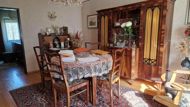 Traditioneller Essbereich mit dunklem Holzschrank, Esstisch und gemustertem Teppich, der eine gemütliche Atmosphäre schafft.