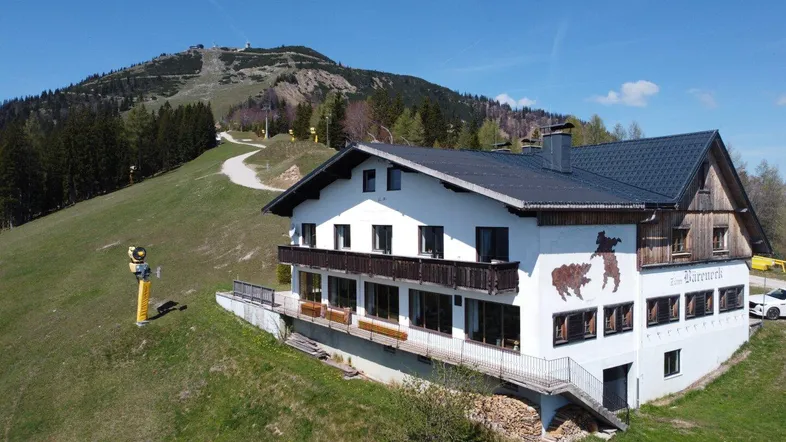Großes Gebäude im alpinen Stil mit Balkonen und Blick auf die Skipiste und die Berge.