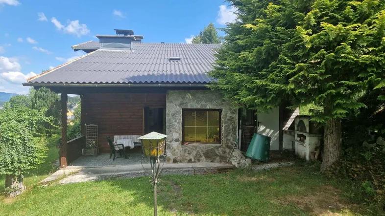 Rustikales Haus mit Steinfassade, überdachter Terrasse und einem traditionellen Außenofen im grünen Garten.