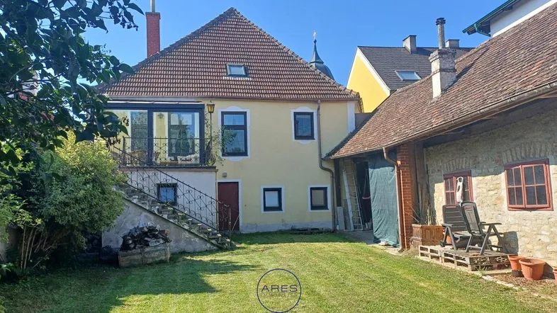 Ansicht des Hauses von hinten mit großem Gartenbereich und Außentreppe zum oberen Stockwerk.
