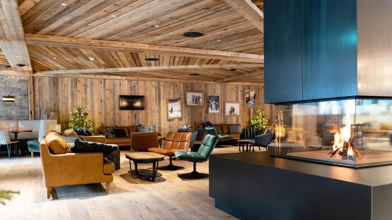 Gemütlicher Loungebereich mit modernem Kamin, Holzwänden und bequemen Sitzgelegenheiten.