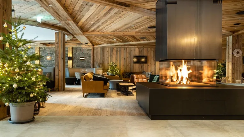 Gemütlicher Loungebereich mit modernem Kamin, Holzvertäfelung und festlicher Weihnachtsdekoration.