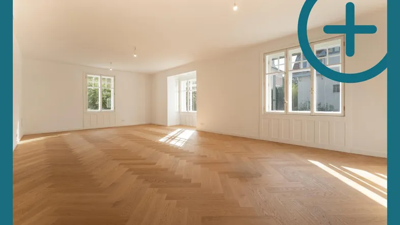 Helles, geräumiges Zimmer mit Fischgrätparkett und großen Fenstern, das viel Tageslicht hereinlässt.