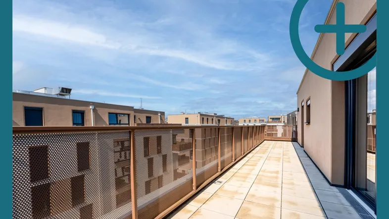 Geräumige Dachterrasse mit Fliesenboden und Blick auf moderne Wohngebäude unter blauem Himmel.
