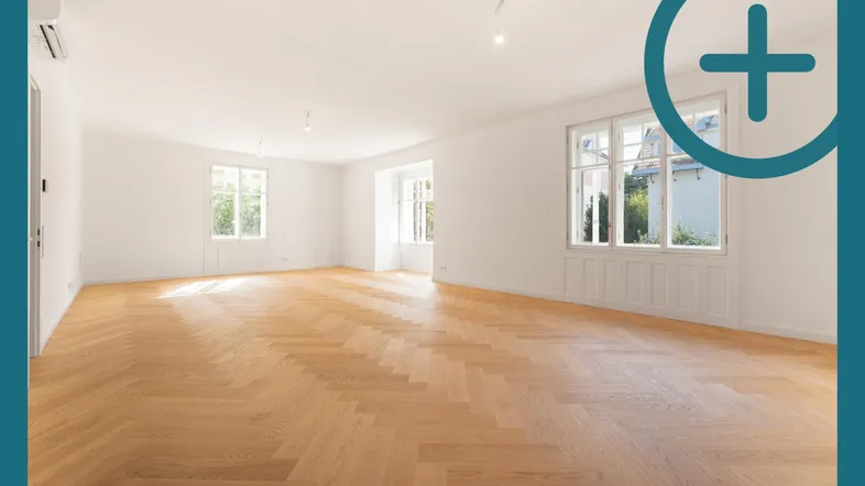 Helles, geräumiges Zimmer mit Fischgrätparkett und großen Fenstern, ideal als Wohnbereich.
