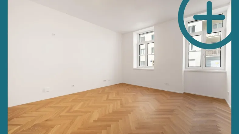 Helles, leeres Zimmer mit Fischgrätparkett und zwei Fenstern, bereit zur individuellen Gestaltung.