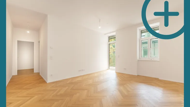 Helles, leeres Zimmer mit Fischgrätparkett und Zugang zu einem französischen Balkon.