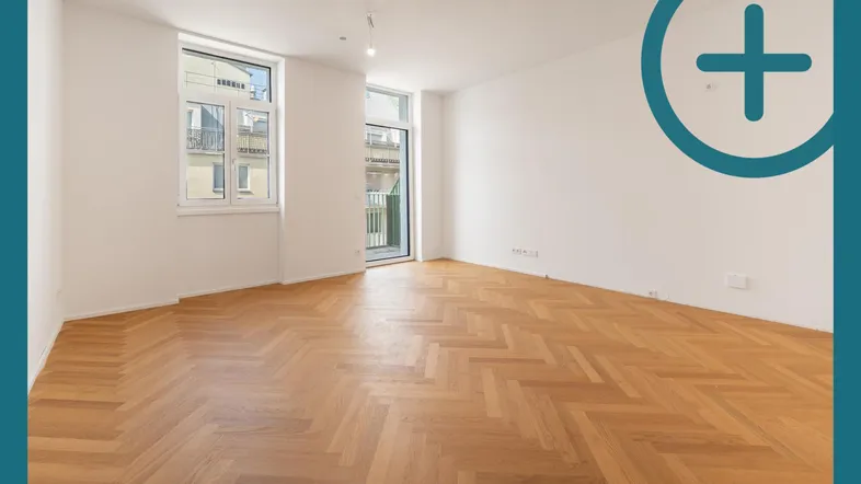 Helles Zimmer mit Fischgrätparkett und Zugang zu einem französischen Balkon.