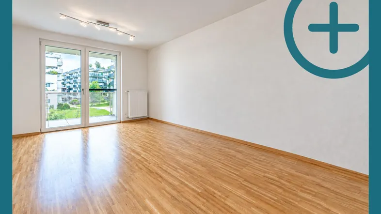 Helles Zimmer mit Parkettboden und Zugang zu einem Balkon mit Blick auf die umliegenden Gebäude.