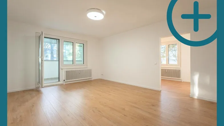Helles, leeres Wohnzimmer mit Laminatboden und Zugang zu einem Balkon.